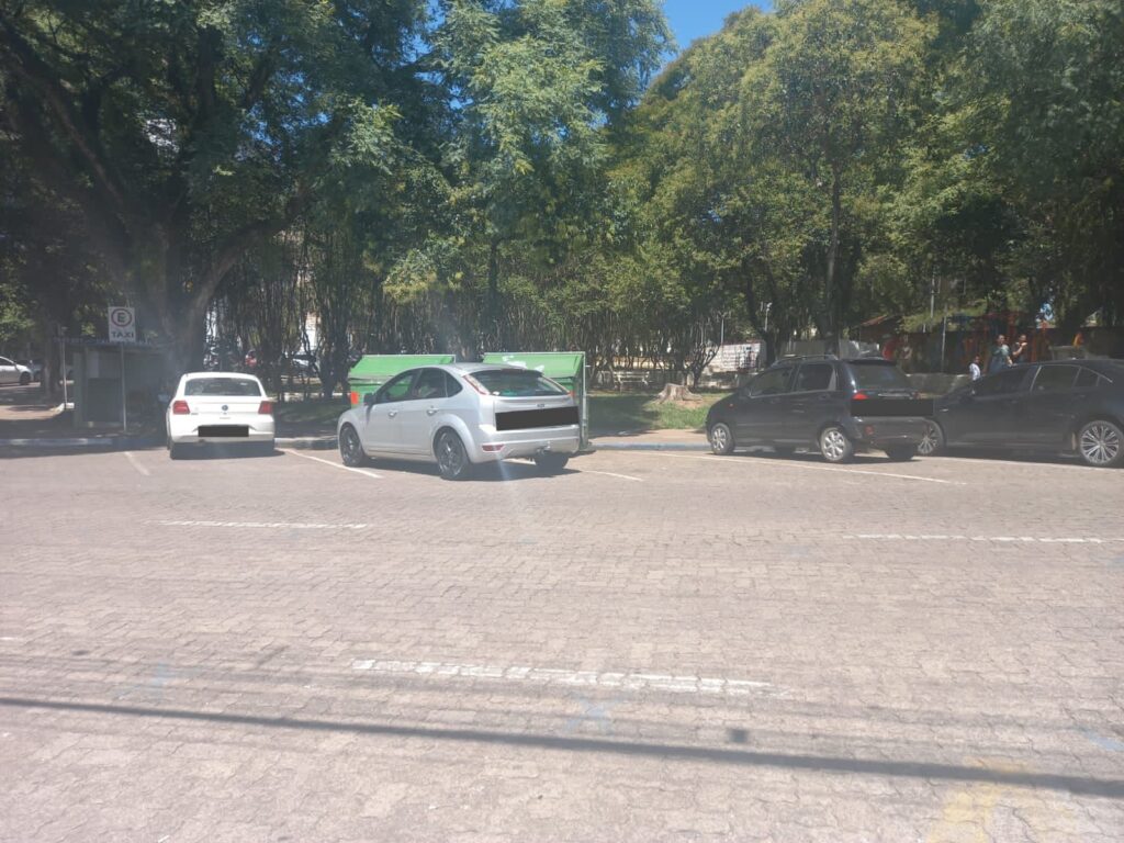 três carros estacionados na rua com dois contêineres