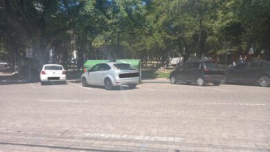 três carros estacionados na rua com dois contêineres