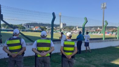 três policia de costa olhando para um campo de futebol