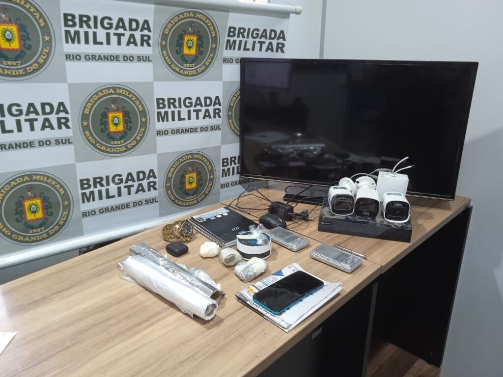 mesa com objetos em cima e na parede o logo da brigada militar
