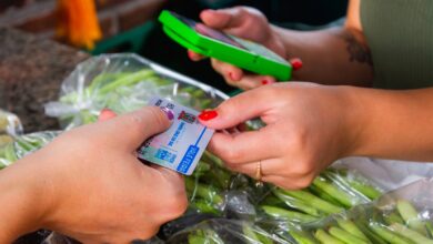 Mão com cartão entregando para cobrança, maquina verde de cartão de credito